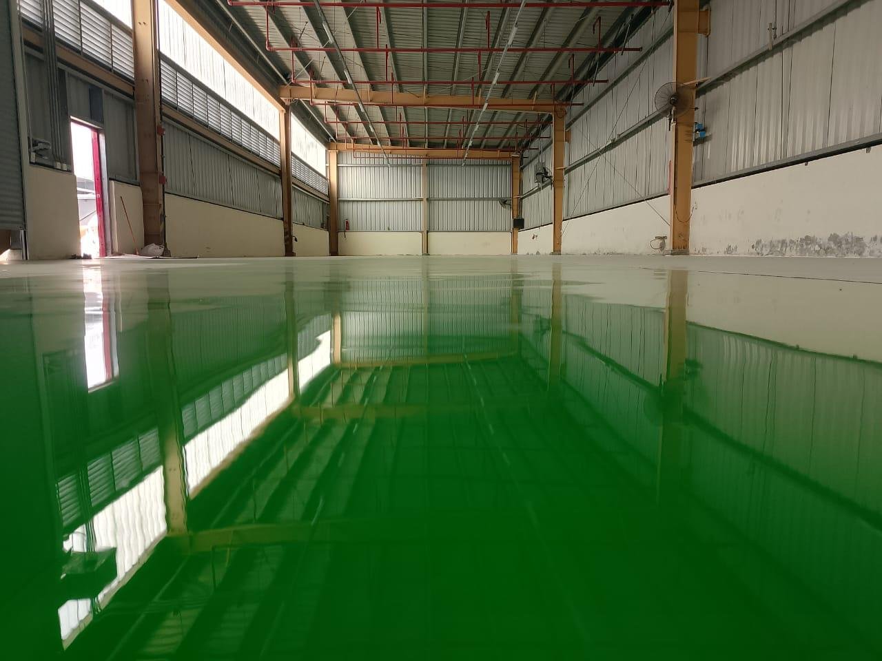 Glossy green self-leveling epoxy floor installed in a Faisalabad warehouse